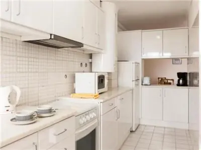 a white kitchen with white cabinets and a microwave at Superb Apartments 2 Bedroom in Olhos de Água