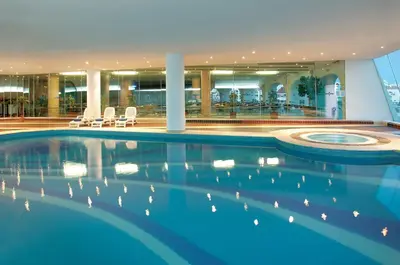 a large swimming pool in a building with chairs at Spectacular Albufeira 2 Bedroom apartment in the city center in Albufeira