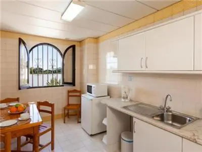 a kitchen with white cabinets and a table and a sink at Fantastic Apartments 1 Bedroom in Olhos de Água