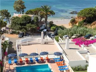 a swimming pool with chairs and umbrellas and the ocean at Fantastic Apartments 1 Bedroom in Olhos de Água