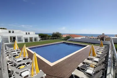 a view of a swimming pool with chairs and a building at Beach Side Apartment in Albufeira