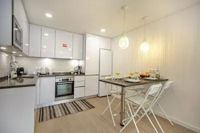a kitchen with white cabinets and a table with chairs at Apartment Sandi in Albufeira