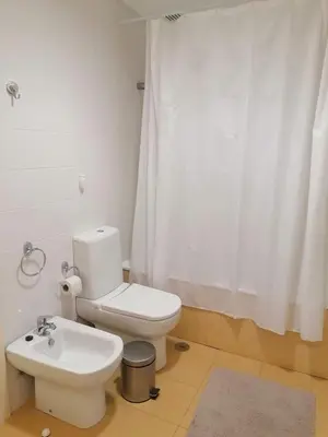 a bathroom with a white toilet and a sink at Recanto de Férias in Albufeira