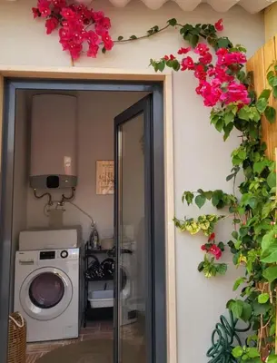 a bathroom with a washing machine and flowers on the wall at Casa Melro in Faro
