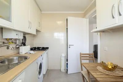 a kitchen with white cabinets and a sink and a table at TAC - Bliss Vilamoura in Quarteira