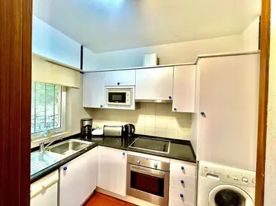 a white kitchen with a sink and a microwave at Heart of Quinta do Lago ! in Faro