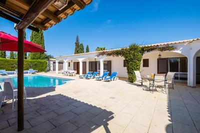 a patio with a pool and chairs and an umbrella at Villa Brid in Albufeira
