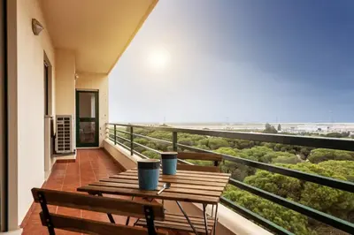 a balcony with a wooden table and a view of the beach at Blife RYA private rooms - Airport stay in Faro