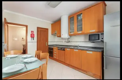 a kitchen with wooden cabinets and a table with a sink at Blife RYA private rooms - Airport stay in Faro