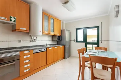 a kitchen with wooden cabinets and a table and chairs at Blife RYA private rooms - Airport stay in Faro