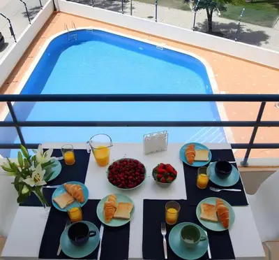 a table with plates of food next to a pool at Atlantic Pearl by the Sea - Quarteira in Quarteira