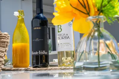 a table with two bottles of wine and a vase with flowers at Casa Merrigan in Albufeira