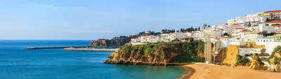 a group of white houses on a hill next to the ocean at Casa Merrigan in Albufeira