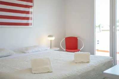 a white bed with two towels on it with a red chair at Centralgarve - Excellent & Peaceful Villa in the Center of Vilamoura in Vilamoura