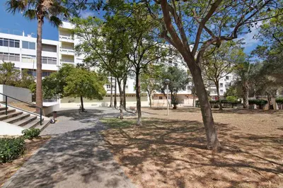 a park with trees in front of a building at Casa da Saudade no centro de Faro in Faro