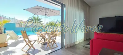 a living room with a table with an umbrella at Maison avec piscine et jacuzzi in Guia