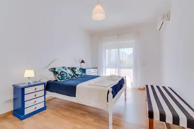 a bedroom with a blue and white bed and a window at Spacious 2 bedroom apartment in Faro in Faro