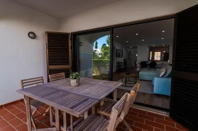 a wooden table and chairs in a living room at Beachside Bliss T2 with Pool & Beach Access by Drago Rentals in Albufeira