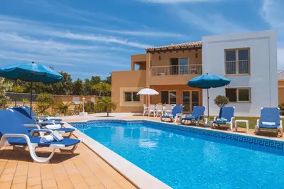 a pool with chairs and umbrellas next to a house at Villa Maya Bay by Algarve Vacation in Guia