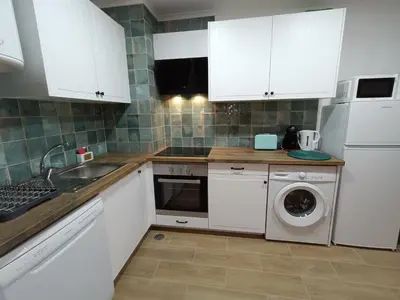 a kitchen with white cabinets and a washing machine at Apartamento Praia da Gale in Albufeira