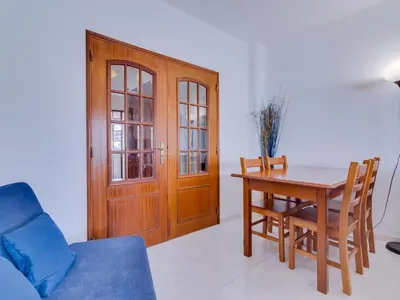 a living room with a table and a wooden door at Central 2bdr apartment in Quarteira in Quarteira