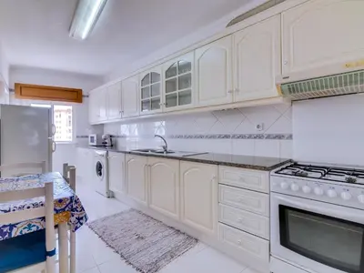 a kitchen with white cabinets and white appliances at Central 2bdr apartment in Quarteira in Quarteira