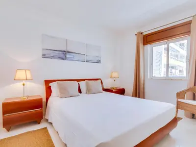 a white bedroom with a large bed and a window at Central 2bdr apartment in Quarteira in Quarteira