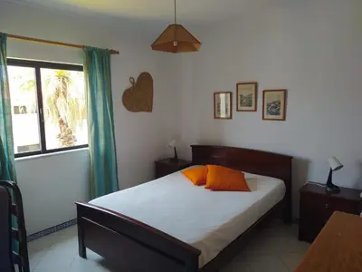 a bedroom with a bed with orange pillows and a window at SolNascenteII-Vilamoura in Quarteira