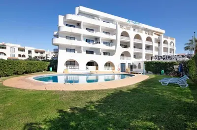 a large white building with a swimming pool in front of it at Torga Apartment in Albufeira