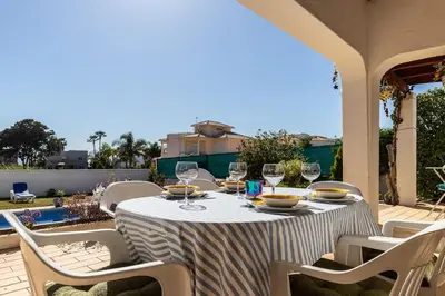 a table with chairs and wine glasses on a patio at NEW! 4bedroom Villa - Private Pool and Sea view in Guia