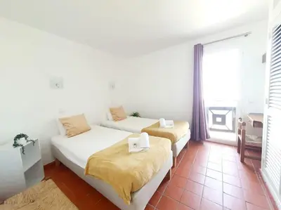 a room with two beds and a large window at Apartamento do Moinho acesso à Piscina in Albufeira