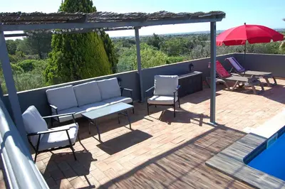 a patio with chairs and a table and an umbrella at Charmante Villa mit 3 Schlafzimmer und Blick zum Meer in Santa Bárbara de Nexe