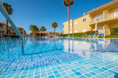 a swimming pool at a resort with palm trees at Cosy apartment in Jardins Vale de Parra in Guia