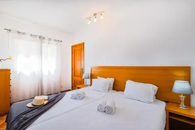 a bedroom with a bed with two hats and slippers on it at Cosy apartment in Jardins Vale de Parra in Guia
