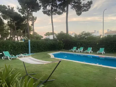 a hammock and chairs next to a swimming pool at Moradia VSSG em Vilamoura in Quarteira