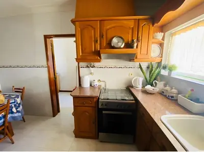 a kitchen with wooden cabinets and a stove at Moradia VSSG em Vilamoura in Quarteira