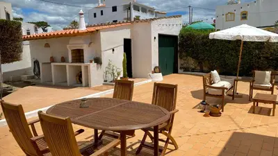 a patio with a table and chairs and an umbrella at Casa dos Arcos in Olhos de Água