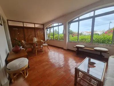 a living room with a table and chairs and windows at Casa dos Arcos in Olhos de Água