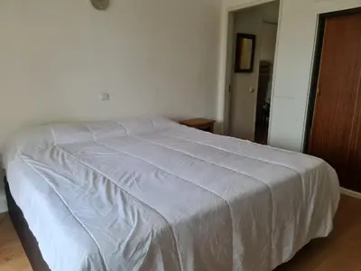 a bed in a bedroom with a white blanket on it at Casa dos Arcos in Olhos de Água