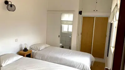 a bedroom with two beds and a door to a bathroom at Casa dos Arcos in Olhos de Água