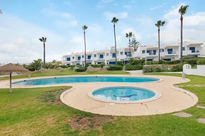 a pool in front of a building with palm trees at Oura Southvilla Algarve in Albufeira