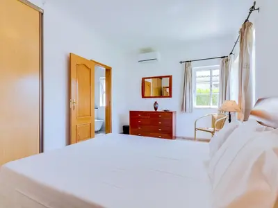 a white bedroom with a bed and a window at AL Casa Raha in Quinta do Lago