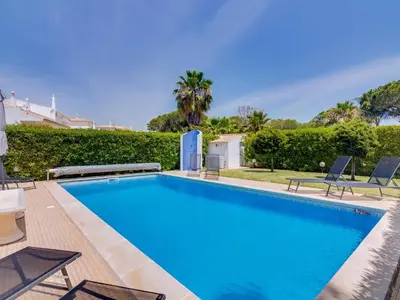 a swimming pool with blue water in a yard at AL Casa Raha in Quinta do Lago