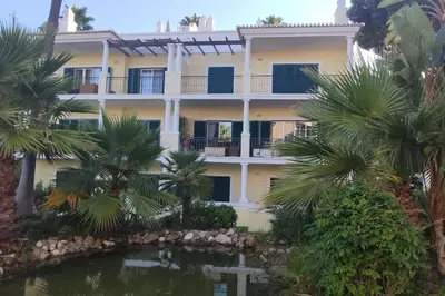 a building with palm trees in front of it at Private luxury apartment Vale do Lobo in Almancil