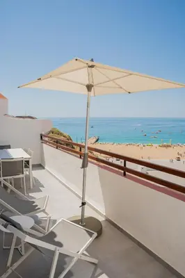 a balcony with chairs and an umbrella and a beach at MUPA Apartments in Albufeira