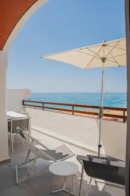a patio with a chair and an umbrella and the beach at MUPA Apartments in Albufeira
