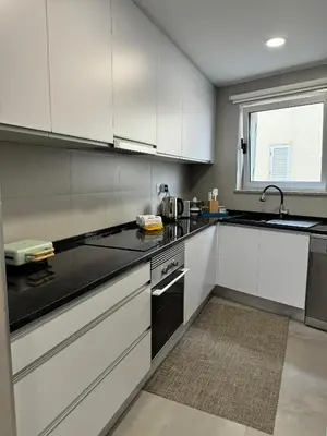 a kitchen with white cabinets and black counter tops at Marina Gemeos - Vilamoura Center by HD Properties in Vilamoura