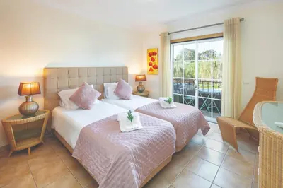 a bedroom with two beds and a window at Stylish 2BR Apartment with Pool Parking & WiFi in Albufeira