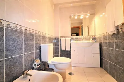 a bathroom with a toilet and a sink and a mirror at Stylish 2BR Apartment with Pool Parking & WiFi in Albufeira