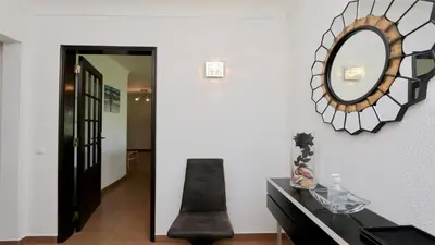 a mirror on the wall next to a black chair at Villa Lotus, CD 283 - Cleverdetails in Vilamoura